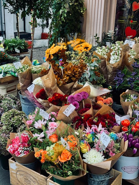 A vibrant display of freshly arranged floral bouquets on a flower shop's outdoor stand, featuring a variety of blooms such as sunflowers, pink lilies, red carnations, white chrysanthemums, purple iris